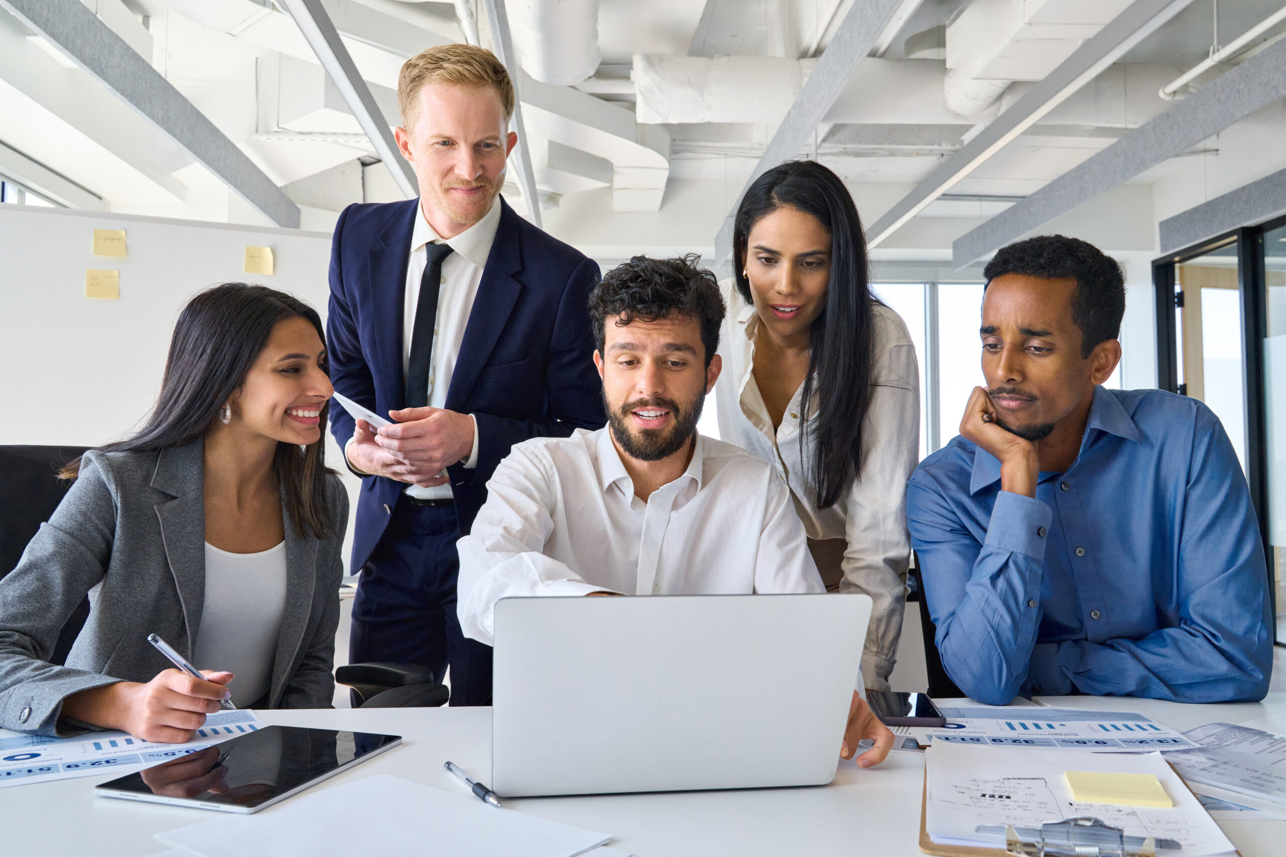 Busy diverse professional business people group looking at laptop in office.